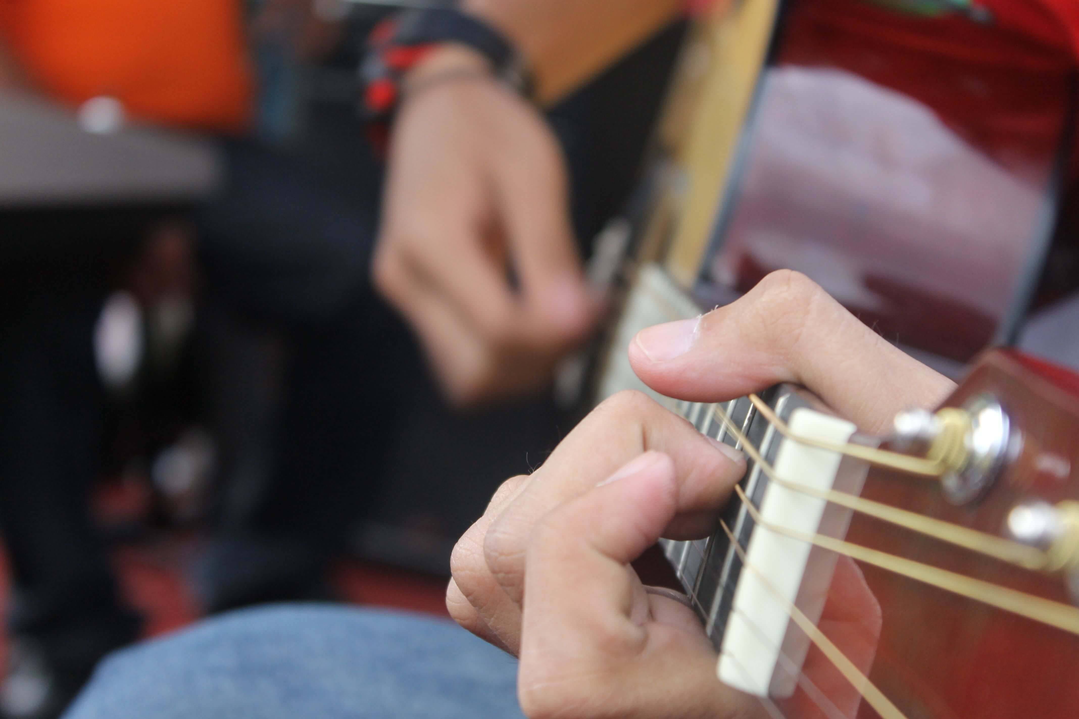 Cận cảnh b&agrave;n tay gảy d&acirc;y đ&agrave;n guitar acoustic dưới &aacute;nh đ&egrave;n m&agrave;u